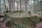 Las redes de camuflaje se cubren de un vehículo militar para reducir su sombra.