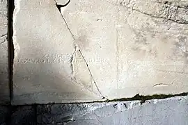 Una piedra de la puerta, reutilizada de un monumento más antiguo: se ve una inscripción, actualmente al revés