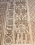Motivos arabescos y piñas junto con inscripciones caligráficas alrededor del mihrab de la Madrasa de Ben Youssef, en Marrakech (siglo XVI)
