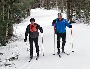 Un esquiador de fondo ciego con guía en un evento regional de Ski for Light.