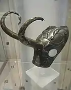 Testera de pony con cuernos. No hay acuerdo si los cuernos son un añadido posterior. El material es bronce y se encuentra profusamente decorado.