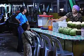 Niño comprando 'agua de coco' en un mercado de Kota Kinabalu