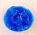 Cristales de CuSO4 pentahidratado creados artificialmente en un vaso plástico.
