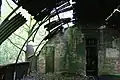 Interior en abandono de un cobertizo Nissen; las láminas de hierro corrugado que forman las paredes y el techo están soportadas por tabiques de ladrillo y vigas metálicas