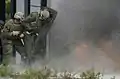 Los Marines de EE. UU. Se protegen detrás de un escudo protector durante una ruptura explosiva de una puerta