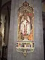 San Cenobio (sentado), con sus diáconos San Crescencio y San Eugenio (a sus pies). Pintura en un pilar del Duomo (Catedral de Santa María del Fiore, Florencia).