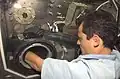 Visión sobre el hombro del astronauta Pedro Duque de la Agencia Espacial Europea (ESA) mientras trabaja en Microgravity Science Glovebox para el experimento Cervantes PromISS 2 en el Laboratorio Destiny de EE. UU. Durante operaciones conjuntas con las tripulaciones de la Expedición 7 y Expedición 8.