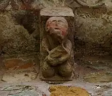 Canecillo que representa a un músico probablemente tocando la viola.
