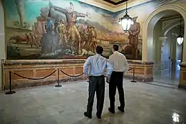 Dos personas observan El trágico preludio de John Steuart Curry