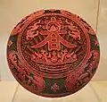 Una caja roja lacada de la Dinastía Qing con el carácter chino "primavera" inscrito en la parte frontal, que data del reinado del emperador Qianlong (1736-1795)