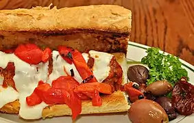Un sándwich de albóndigas con salsa marinara, mozzarella y pimientos asados.