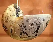 Concha de nautilo tallada y pintada con escenas de fantasía de figuras humanas y animales.