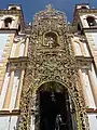 Fachada de la iglesia decorada con un arco de flores y plantas para la fiesta patronal