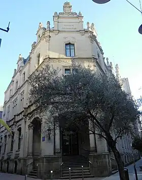 Edificio central de Correos en la calle con el olivo delante.