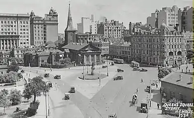 Foto aérea en blanco y negro del cruce entre las calles Macquario y King, cuando el tráfico podía pasarse de una a la otra. Los autobuses y otros vehículos se encuentran en las calles y se puede ver un edificio que ahora está demolido
